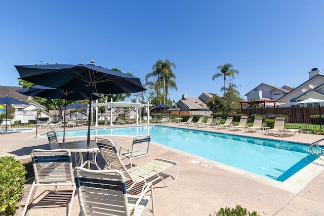 community pool with a patio area and fence