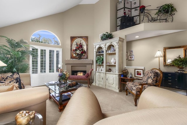 living area featuring a lit fireplace, high vaulted ceiling, and carpet