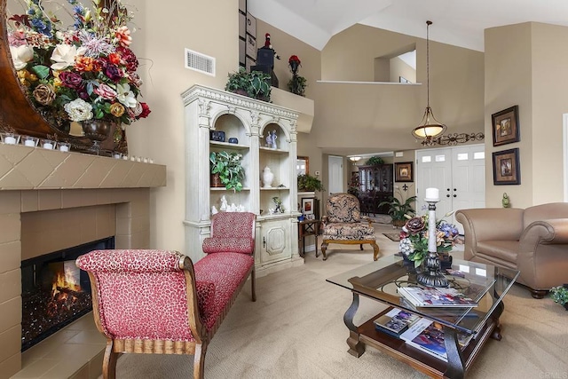 living room featuring visible vents, a tile fireplace, high vaulted ceiling, and carpet