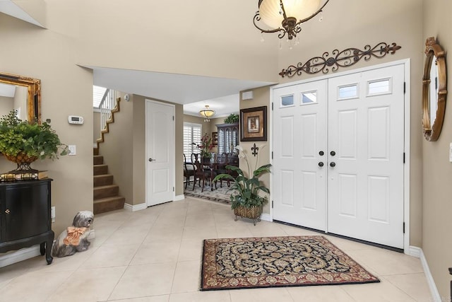 entrance foyer featuring stairway, light tile patterned floors, and baseboards