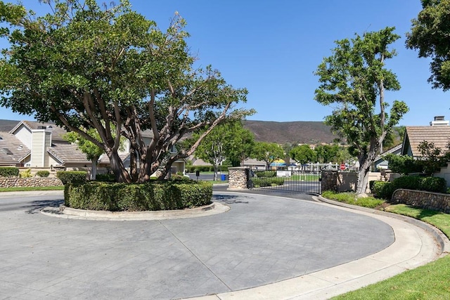 view of road featuring curbs, a mountain view, a gated entry, and a gate