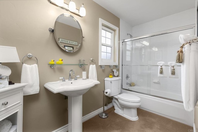 bathroom featuring a sink, toilet, baseboards, and bath / shower combo with glass door