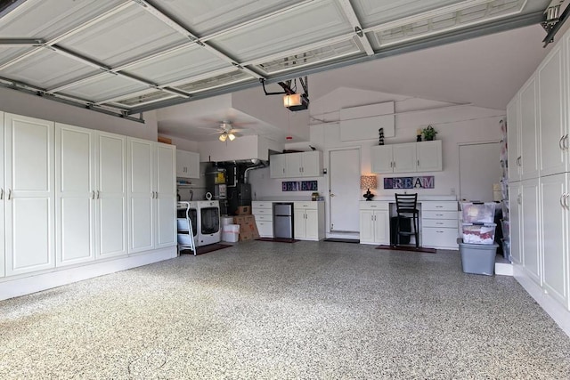 garage featuring washer and dryer, a garage door opener, ceiling fan, and water heater