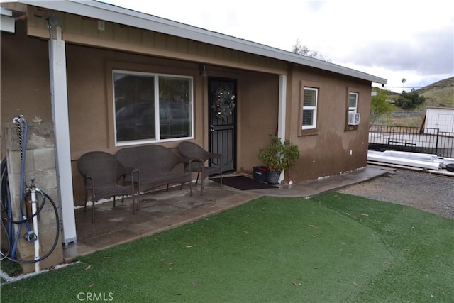 property entrance featuring a patio area, stucco siding, cooling unit, and fence