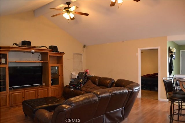 living area featuring wood finished floors, vaulted ceiling with beams, and a ceiling fan