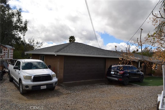 view of side of home with driveway, a shingled roof, and an attached garage