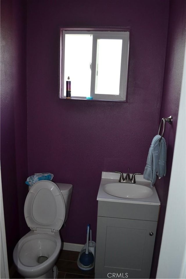 bathroom featuring vanity, toilet, and baseboards