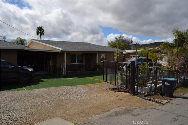 ranch-style house with fence, a front yard, driveway, a mountain view, and a gate