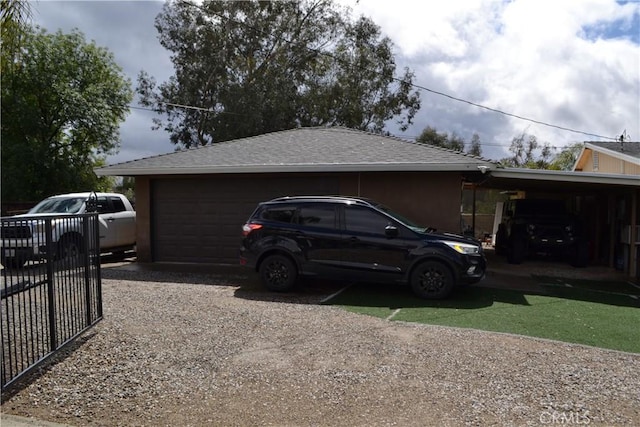 view of side of property with fence, roof with shingles, a garage, a carport, and driveway