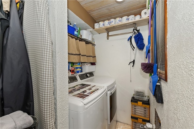 washroom featuring a textured wall, wooden ceiling, laundry area, and washer and clothes dryer