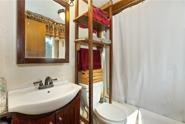 bathroom with curtained shower, vanity, toilet, and a textured wall