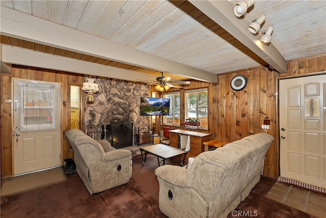 tiled living room with a ceiling fan, beamed ceiling, a fireplace, and wood walls