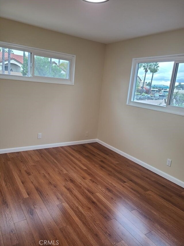 empty room with baseboards, plenty of natural light, and hardwood / wood-style flooring