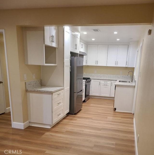 kitchen with range with gas cooktop, freestanding refrigerator, light wood-style floors, and a sink