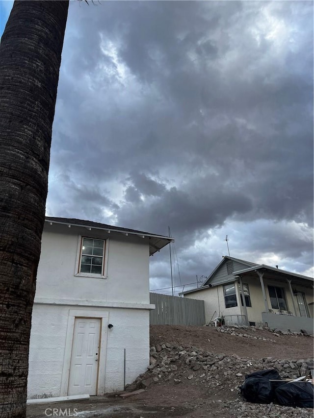 view of side of home featuring stucco siding and fence