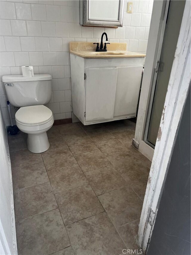 full bathroom featuring vanity, tile walls, toilet, and a stall shower