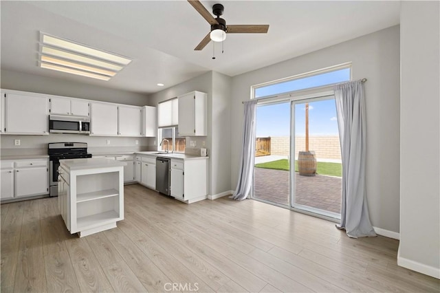 kitchen featuring baseboards, open shelves, stainless steel appliances, light countertops, and light wood-type flooring