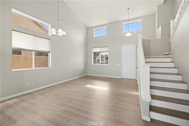 entryway with stairway, high vaulted ceiling, baseboards, and wood finished floors