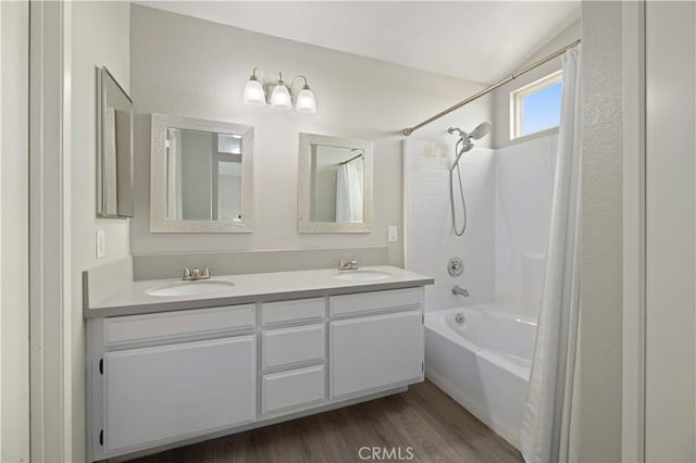 bathroom featuring double vanity, wood finished floors, shower / tub combo with curtain, and a sink