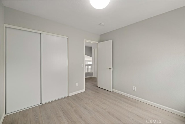 unfurnished bedroom with a closet, baseboards, and wood finished floors