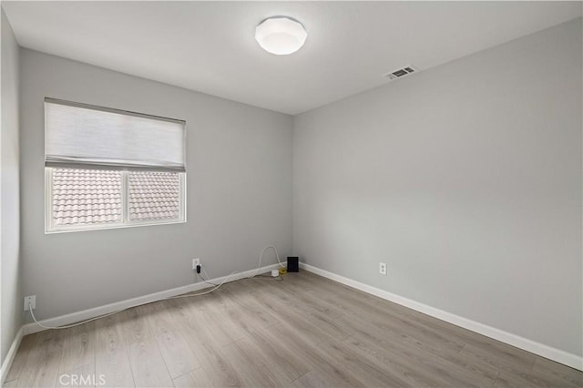 unfurnished room with visible vents, wood finished floors, and baseboards