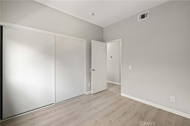 unfurnished bedroom with visible vents, baseboards, a closet, and wood finished floors