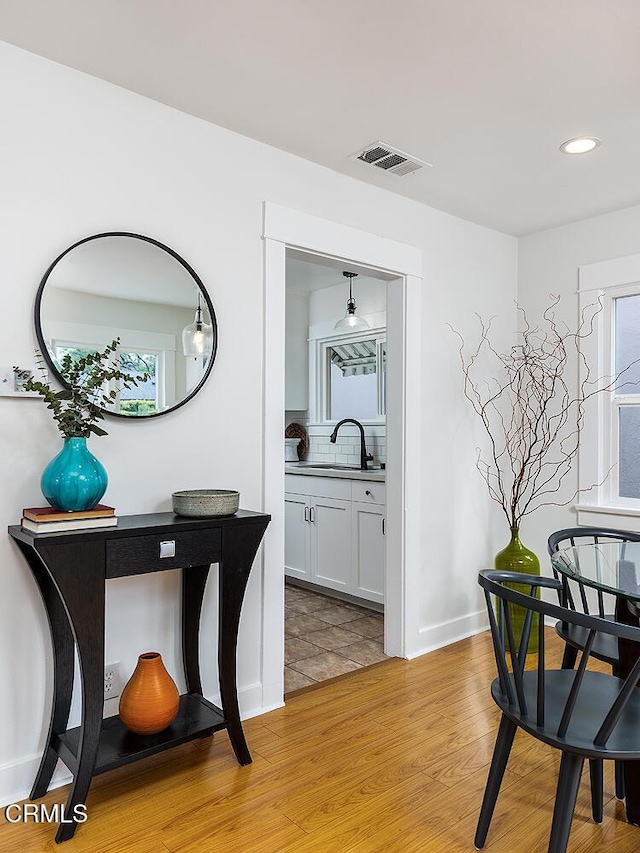 interior space featuring visible vents, baseboards, light wood-type flooring, recessed lighting, and a sink