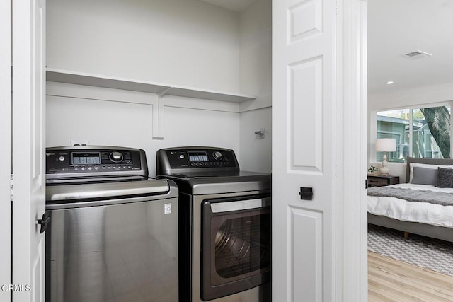 laundry area featuring visible vents, wood finished floors, washing machine and dryer, and laundry area