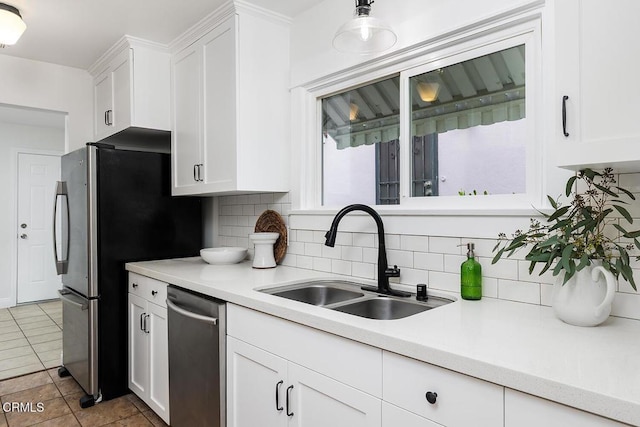 kitchen with a sink, tasteful backsplash, white cabinetry, appliances with stainless steel finishes, and light countertops