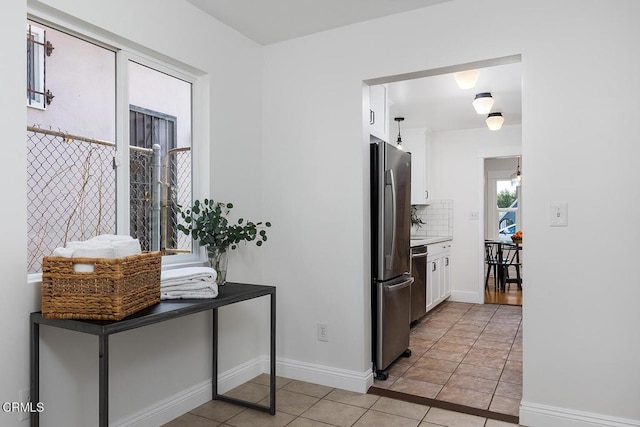 kitchen with tasteful backsplash, baseboards, light tile patterned floors, appliances with stainless steel finishes, and white cabinetry