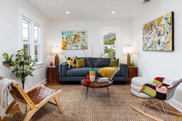 living room with recessed lighting, visible vents, baseboards, and wood finished floors