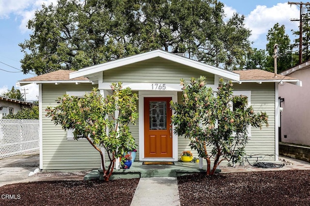 view of front of house with a shingled roof and fence