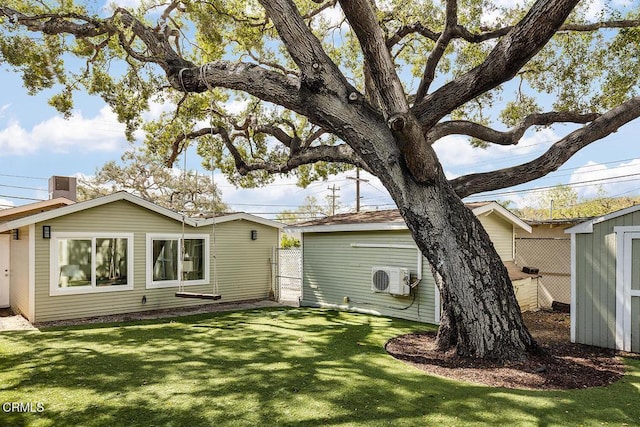 back of property featuring fence, ac unit, a lawn, a storage shed, and an outbuilding