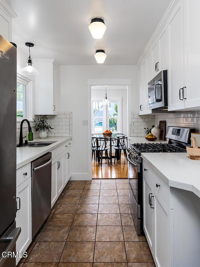 kitchen featuring a sink, light countertops, appliances with stainless steel finishes, white cabinetry, and backsplash