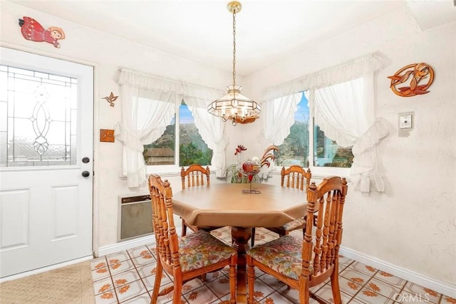 dining room featuring a notable chandelier and baseboards