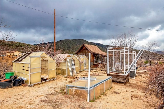 view of yard featuring an outbuilding, a mountain view, and an exterior structure