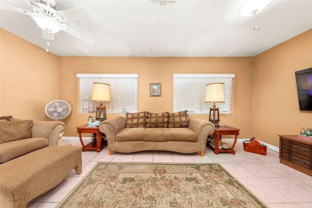 living area featuring baseboards, light tile patterned flooring, and a ceiling fan