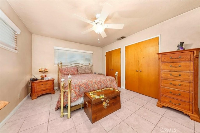 bedroom with light tile patterned floors, visible vents, baseboards, and ceiling fan