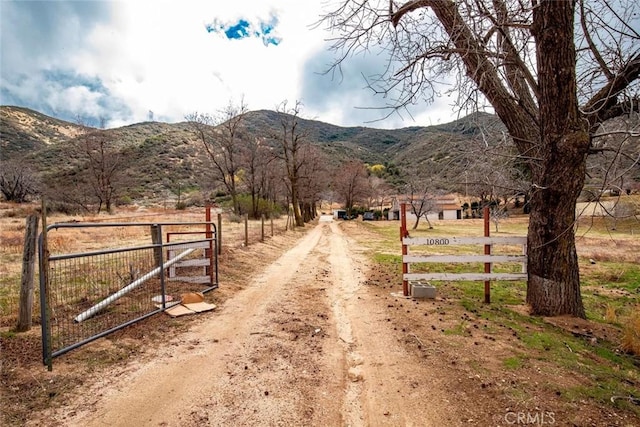 view of road with a rural view, a mountain view, and a gated entry