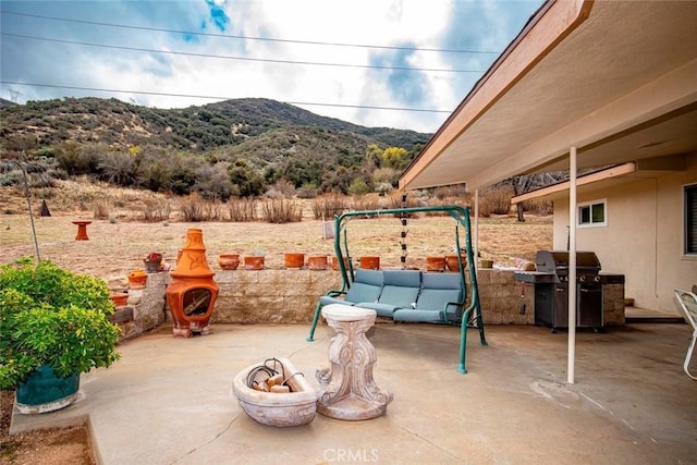 view of patio / terrace with an outdoor living space with a fire pit, area for grilling, and a mountain view