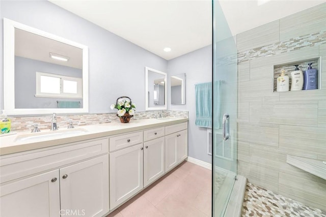 bathroom featuring tile patterned flooring, decorative backsplash, a shower stall, and a sink