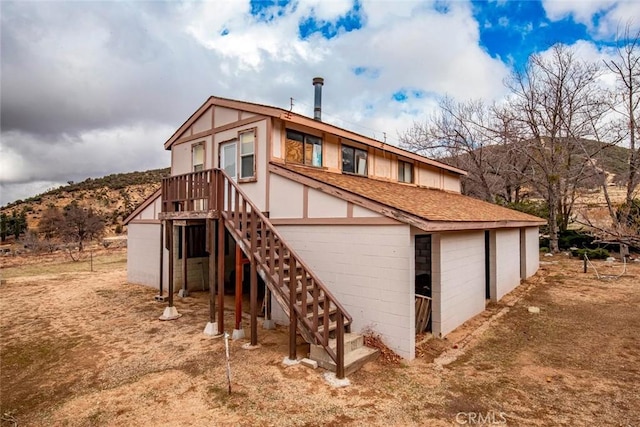 back of house with concrete block siding and stairs