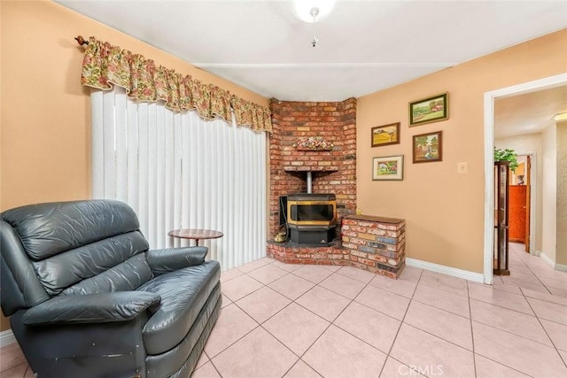 sitting room featuring a wood stove, light tile patterned floors, and baseboards