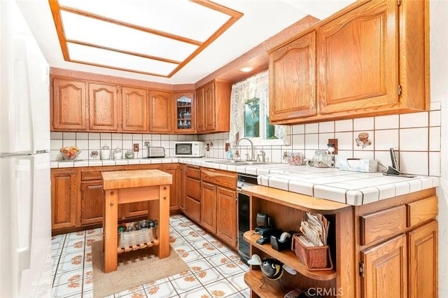 kitchen featuring a sink, white appliances, tasteful backsplash, and tile counters