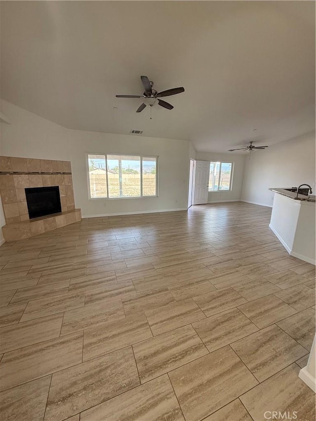 unfurnished living room featuring a fireplace, visible vents, a ceiling fan, and baseboards