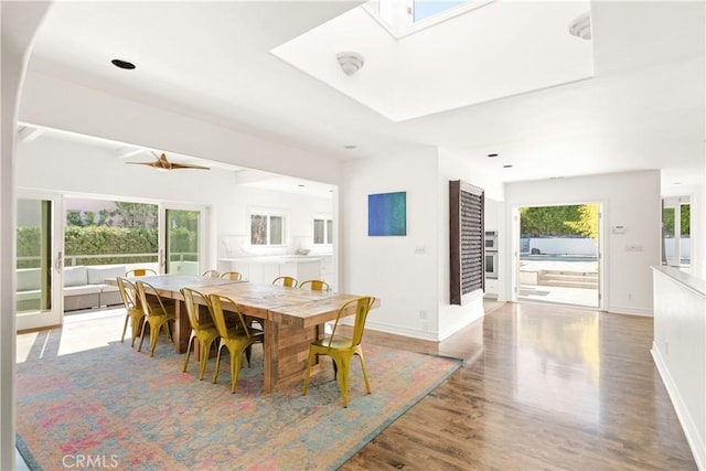 dining area featuring a skylight, wood finished floors, and baseboards