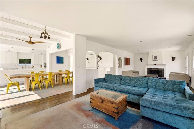 living area with visible vents, beam ceiling, wood finished floors, a fireplace, and baseboards