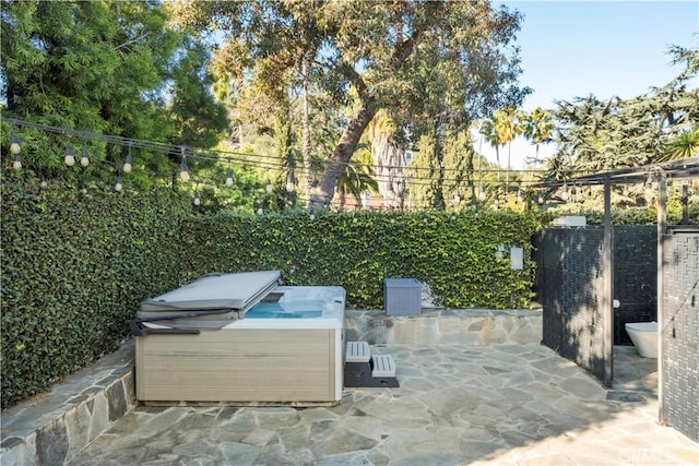 view of patio featuring a hot tub and a fenced backyard