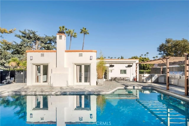 rear view of property featuring an outdoor kitchen, french doors, a pergola, and fence