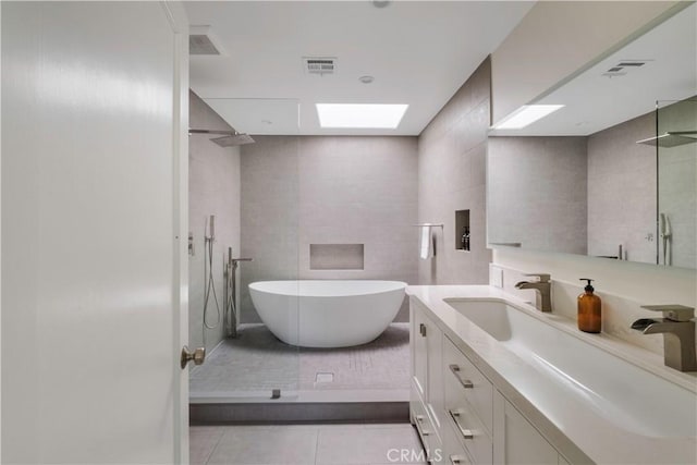 full bathroom featuring vanity, visible vents, tile patterned flooring, a walk in shower, and tile walls